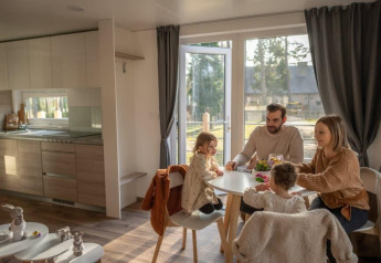 A family enjoys a meal together in Heiberg cottage at Hoge Kempen, Belgium, cozy modern interior view.