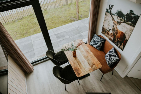 Overhead view of dining nook inside Tiny house XL at Camping Si-Es-An, featuring sofa and deer artwork.