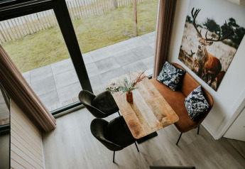 Overhead view of dining nook inside Tiny house XL at Camping Si-Es-An, featuring sofa and deer artwork.