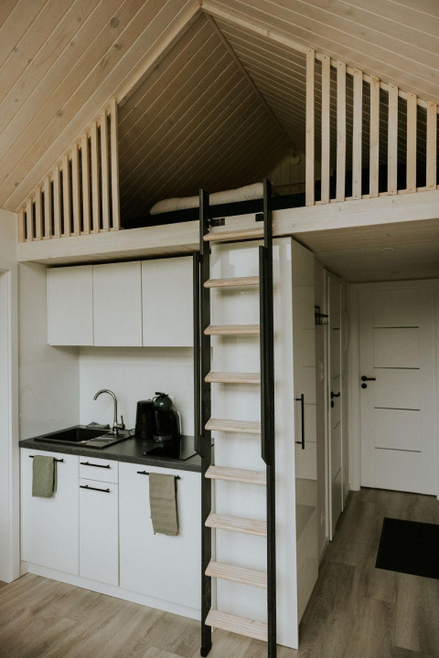 Modern tiny house with loft, ladder, and kitchenette at Camping Si-Es-An in the Netherlands.