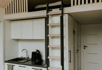 Modern tiny house with loft, ladder, and kitchenette at Camping Si-Es-An in the Netherlands.