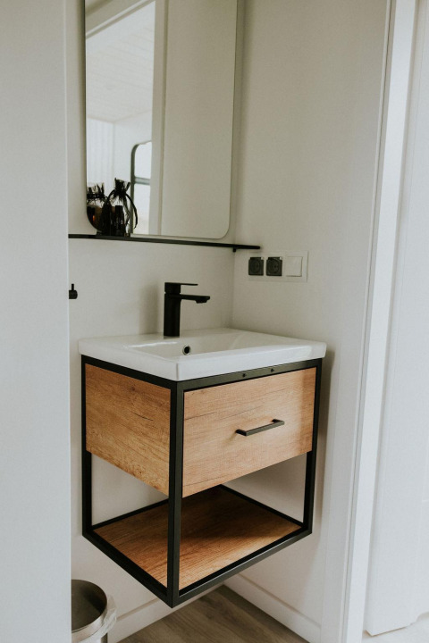 Lavabo moderno con armario de madera y grifo negro en el Tiny house XL en Camping Si-Es-An, Países Bajos.