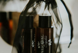 Bottiglie di shampoo marroni in sacchetto di rete nera al Tiny House XL presso Camping Si-Es-An, Paesi Bassi.