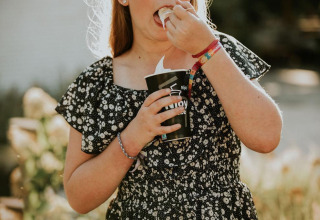 Una ragazza in abito floreale mangia un gelato davanti alla Tiny house XL al Camping Si-Es-An nei Paesi Bassi.