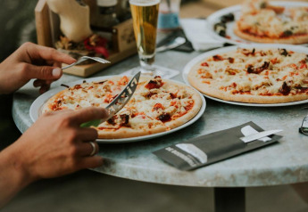 Gustare pizza e bevande a un tavolo all'aperto, tipico di un alloggio glamping con opzioni culinarie.