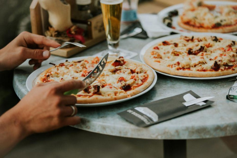 Genieten van pizza en drankjes aan een buitentafel, typisch voor glampingverblijven met eetopties.