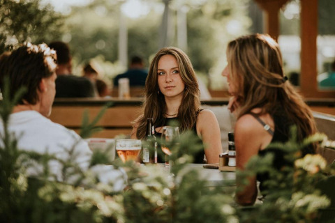 Tres personas sentadas afuera en una mesa disfrutando bebidas en Tiny house XL en Camping Si-Es-An, Países Bajos.