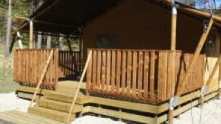 Safari telt med træveranda ved Camping Lou Passavous i Frankrig, omgivet af natur og skov.