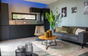 Moderne lodge woonkamer bij Modus Wellness in Hoge Kempen, België, met grijze zetel, plant en stijlvolle decoratie.