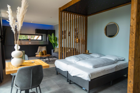 Modern ingerichte lodgekamer in Modus Wellness, Hoge Kempen, België, met bed, keuken en stijlvolle meubels.