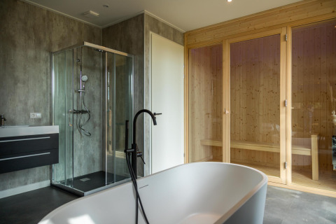 Salle de bain moderne à la lodge Modus Wellness, Hoge Kempen, Belgique avec baignoire, sauna et douche.