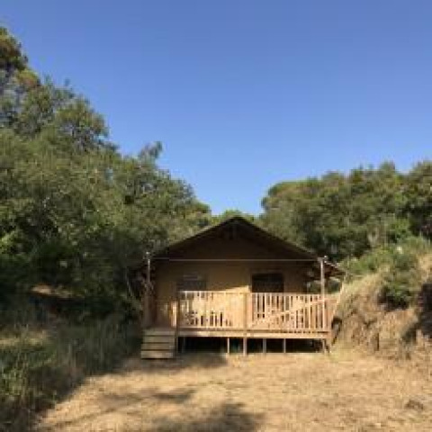 Safari-telt med sanitære faciliteter på Camping Les Lauriers Roses, omgivet af natur og træer i Frankrig.