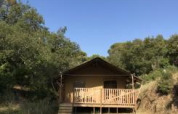 Tienda safari con instalaciones sanitarias en Camping Les Lauriers Roses en Francia, rodeada de naturaleza.