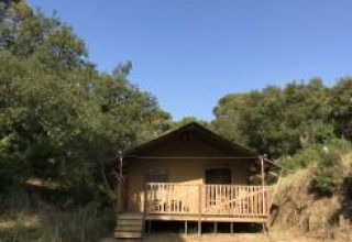 Tienda safari con instalaciones sanitarias en Camping Les Lauriers Roses en Francia, rodeada de naturaleza.