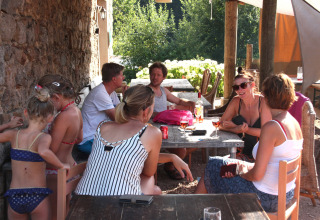 Gruppe voksne og børn nyder udendørs samvær ved bord på Camping Domaine La Chabanne i Frankrig.