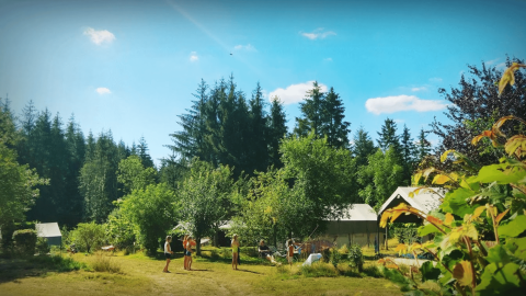 Families genieten in de zon bij Camping Domaine La Chabanne, temidden van bomen in Auvergne-Rhône-Alpes.