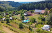 Luftfoto af glamping og gårde omgivet af skove nær Châtel-Montagne i Auvergne-Rhône-Alpes, Frankrig.