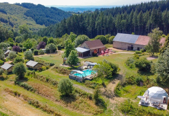 Luftfoto af glamping og gårde omgivet af skove nær Châtel-Montagne i Auvergne-Rhône-Alpes, Frankrig.