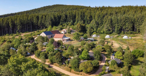Aerial view of Camping Domaine La Chabanne with tents, cabins, and woods in Auvergne-Rhône-Alpes, France.