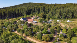Vista aérea de Camping Domaine La Chabanne con tiendas, cabañas y bosque en Auvergne-Rhône-Alpes, Francia.