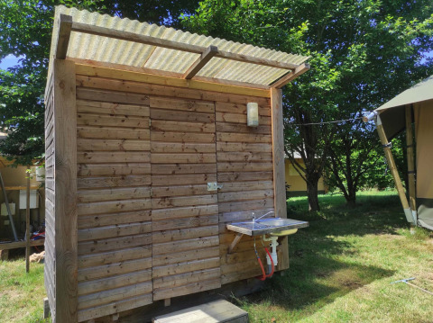 Wooden shed with outdoor sink at Camping Domaine La Chabanne holiday park in Auvergne-Rhône-Alpes, France.