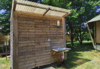 Træhytte med udendørs vask ved Camping Domaine La Chabanne i Auvergne-Rhône-Alpes, Frankrig.