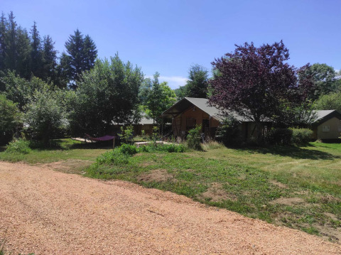 Vista de cabañas y vegetación en Camping Domaine La Chabanne, un parque de vacaciones en Auvernia-Ródano-Alpes, Francia, en verano.