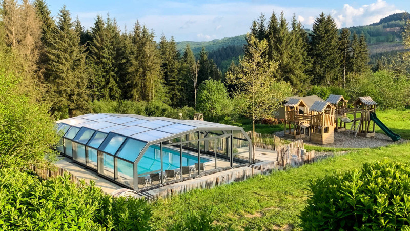 Camping Domaine La Chabanne: Covered pool and playground surrounded by forest in Auvergne-Rhône-Alpes, France.
