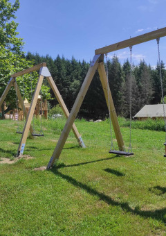 Columpios de madera en área verde en Camping Domaine La Chabanne, Auvergne-Rhône-Alpes, Francia.