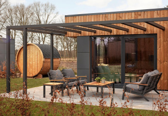 Udendørs terrasse med moderne møbler og træsauna ved Holiday villa Amalia på Hofparken De Bergvennen.