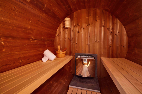 Interior de una sauna de madera con bancos y calentador en Holiday villa Amalia 2 en Hofparken De Bergvennen, Países Bajos.