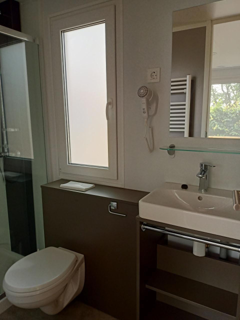 Baño moderno en una tiny house en Kohnenhof, Luxemburgo, con inodoro, lavabo y espejo grande.