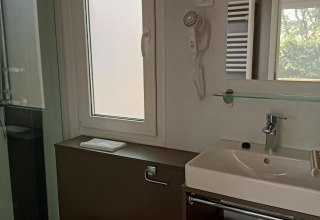 Bagno moderno in una tiny house al Kohnenhof in Lussemburgo con wc, lavandino, specchio e doccia.