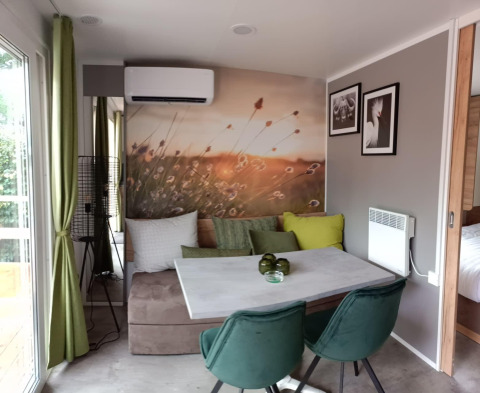 Acogedor comedor en Tiny House en Kohnenhof, Luxemburgo, con mural de naturaleza y sillas verdes.