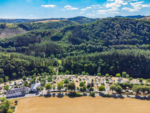 Foto aérea de la Tiny House en Kohnenhof, Luxemburgo, rodeada de bosques verdes y campos abiertos.