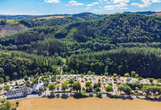 Foto aerea della Tiny House al Kohnenhof in Lussemburgo, circondata da foreste e campi verdi.
