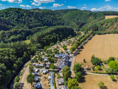 Vista aerea della Tiny House al Kohnenhof in Lussemburgo, circondata da boschi e campi aperti.