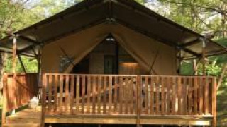 Safari tent with sanitary facilities at Camping Le Gallo Romain in France, surrounded by lush greenery.