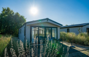 Lodge Velthorst en Poort van Zeeland, Países Bajos, rodeado de césped y árboles bajo un sol radiante.