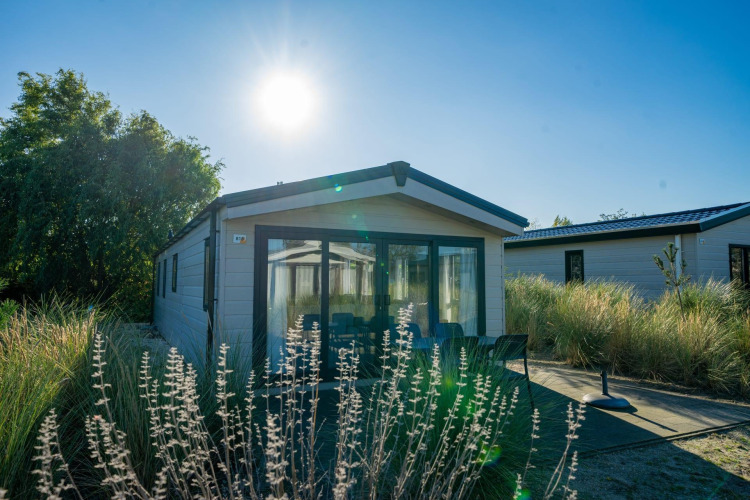 Lodge Velthorst en Poort van Zeeland, Países Bajos, rodeado de césped y árboles bajo un sol radiante.