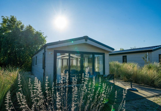 Sonnige Velthorst-Lodge im Poort van Zeeland, Niederlande, umgeben von Gras und moderner Natur.