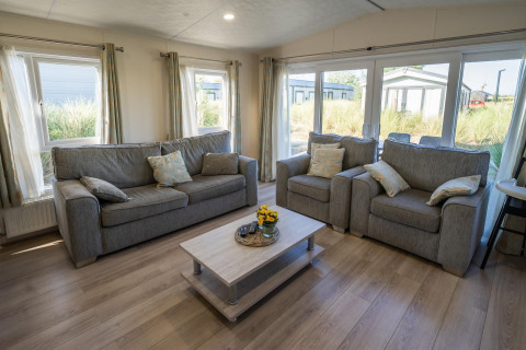 Living room at Velthorst lodge in Poort van Zeeland, Netherlands, with grey sofas, armchairs and large windows.