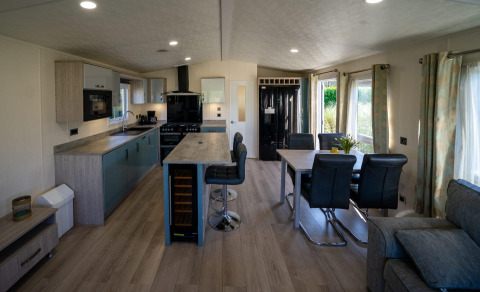 Cocina y comedor modernos dentro de una cabaña Velthorst en Poort van Zeeland, con ventanales y decoración luminosa.