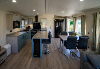 Cocina y comedor modernos dentro de una cabaña Velthorst en Poort van Zeeland, con ventanales y decoración luminosa.