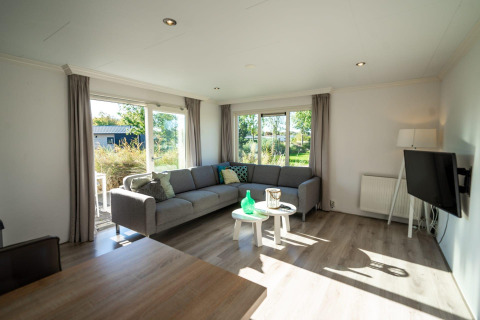 Helles Wohnzimmer mit Ecksofa und großen Fenstern in einer Velthorst Lodge im Poort van Zeeland, Niederlande.