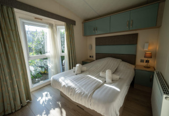 Schlafzimmer in der Velthorst-Lodge in Poort van Zeeland, Niederlande, mit Doppelbett und Aussicht ins Grüne.