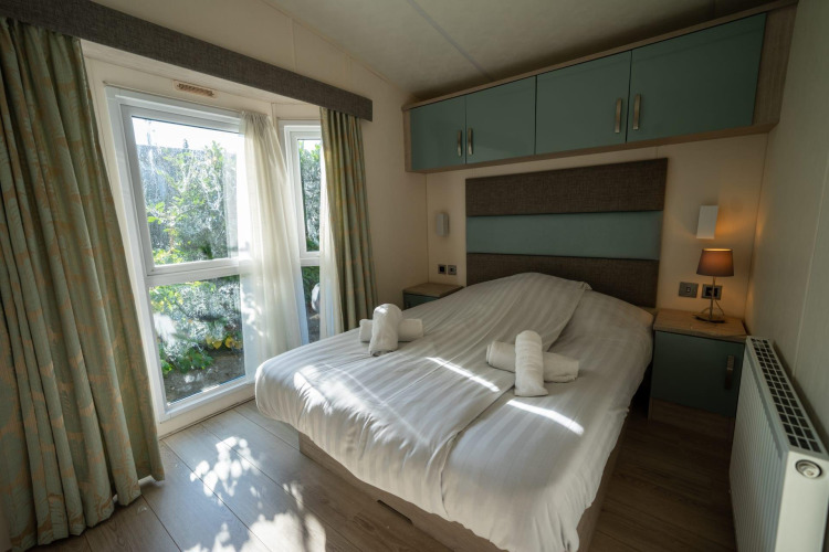 Habitación de la lodge Velthorst en Poort van Zeeland, Países Bajos, con cama doble y ventana al jardín.