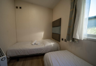 Zwei Einzelbetten in einer kleinen Velthorst-Lodge im Poort van Zeeland, Niederlande, mit Fenster.