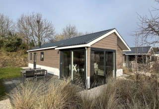 Exterior view of the modern Velthorst lodge at Poort van Zeeland, Netherlands, surrounded by natural scenery.