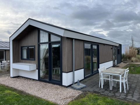 Modernes Velthorst-Lodge im Poort van Zeeland, Niederlande, mit Terrasse und Gartenmöbeln.